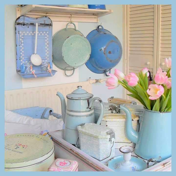 Vintage pastel kitchen with hanging pans, enamel kettles, and pink tulips