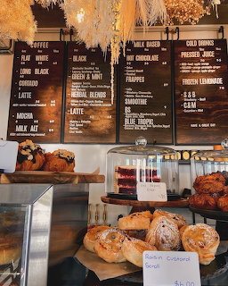 Pastries on a cafe counter below chalkboard menu boards