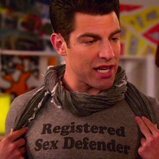 Man wearing a gray slogan shirt and scarf indoors