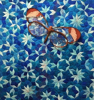 Dragonfly appliqué quilt with blue and teal star pattern background