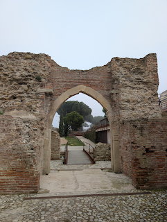 Ancient brick gate ruins with arched opening and weathered stone walls leading to pathway