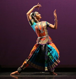 Indian classical dancer posing on stage in a colorful traditional costume