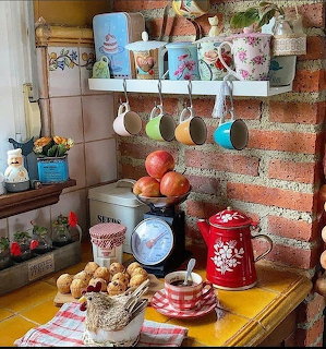 Vintage kitchen scene with hanging mugs, enamel pots, fruits and vegetables on wooden counter against exposed brick wall