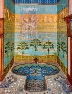 Colorful Art Nouveau tiled bathroom with Egyptian murals, palm trees, ornate basin and decorative mosaic floor