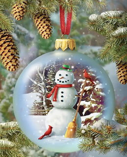 Snow globe ornament with snowman and cardinal hanging on evergreen branch with pine cones