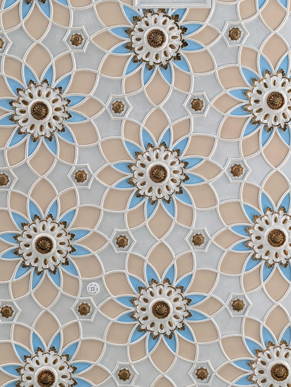Repeating pattern of blue and tan flowers on gray geometric tiles