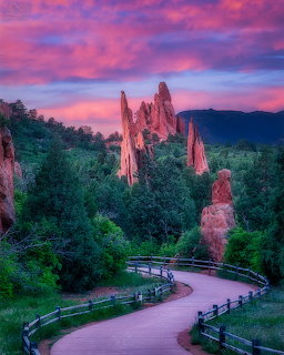 Tall red sandstone rock formations at Garden of the Gods with a curved path and colorful sunset sky