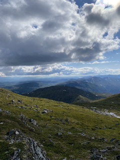 Mountain vista from Ruten Norway showing green slopes and dramatic cloudy sky over distant valleys