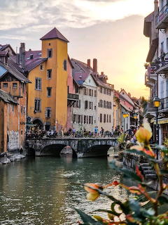 Canal in Annecy old town with colorful buildings and bridge at sunset