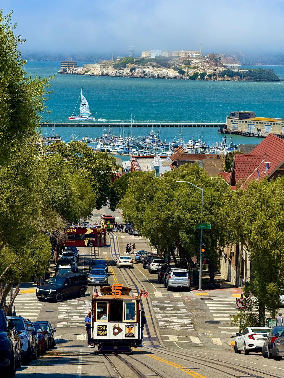 Cable car on steep San Francisco street with Alcatraz Island and bay in background