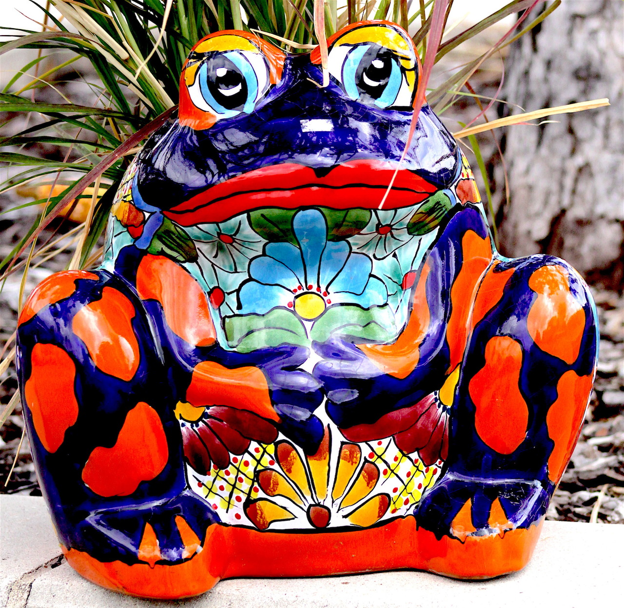 Colorful ceramic frog figurine with orange and blue patterns and floral designs