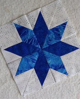 Blue and white Lemoyne star quilt block on textured white fabric