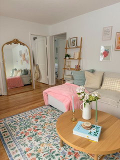 Cozy living room with sofa, floral rug, round coffee table, and large ornate mirror