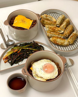 Breakfast tray with fried egg, toast, omelette, greens, and tea in bowls