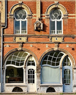 Art Nouveau building facade with curved windows and decorative ironwork on red brick
