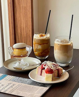 Cafe table with two iced coffee drinks, strawberry cream cake, and a small custard dessert