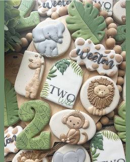 Safari-themed decorated sugar cookies with lion, elephant, giraffe, and monkey for a second birthday party