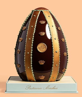 Decorated chocolate Easter egg with gold bands on a display base