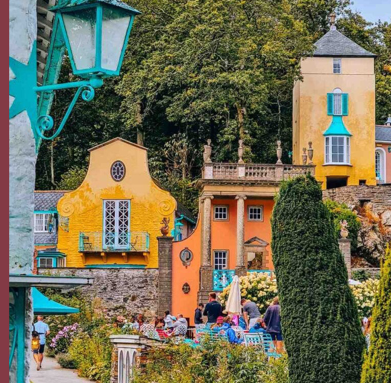 Colorful village buildings with tower, topiary, and tourists in Portmeirion, Wales