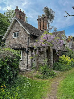 Historic stone cottage with flowering wisteria and garden path in English countryside
