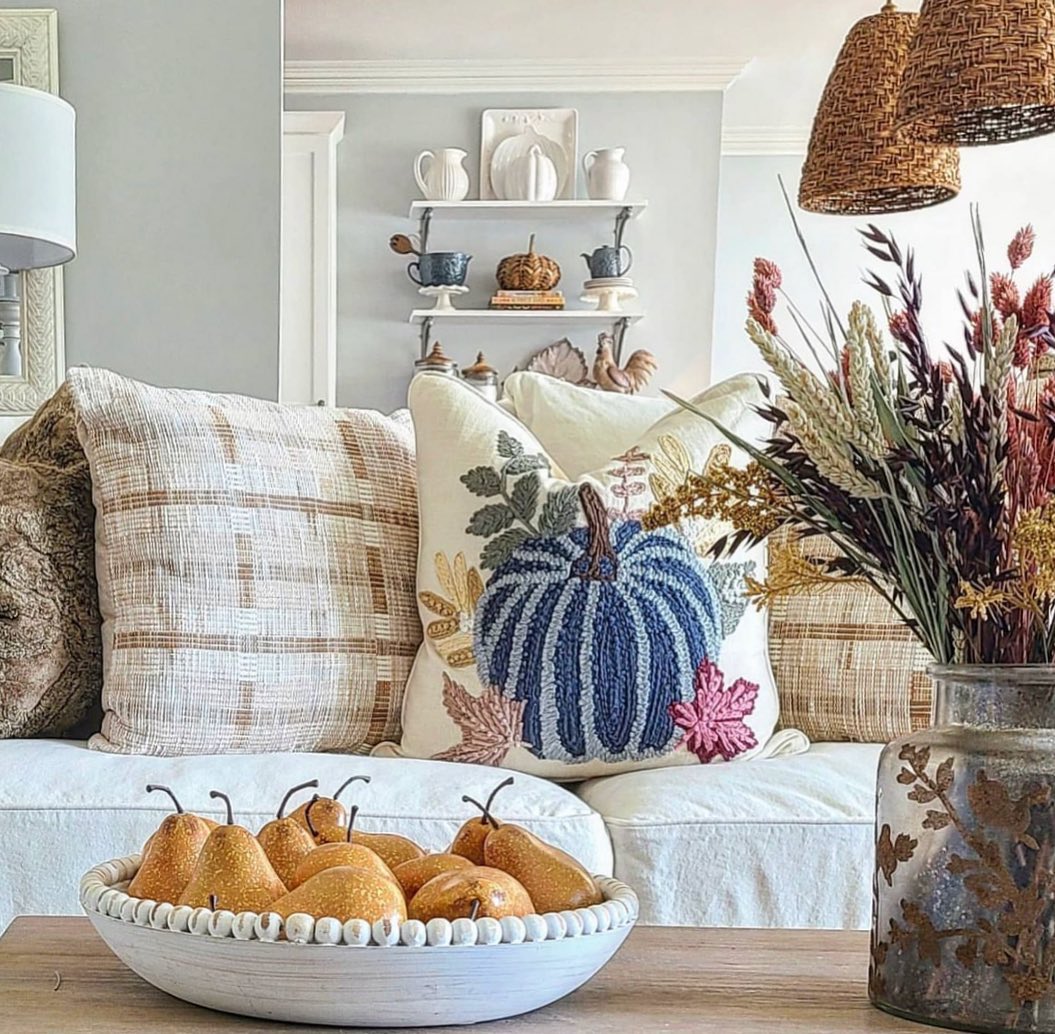Cozy autumn living room with pumpkins, plaid pillows, dried flowers and wicker lamp