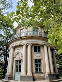 Neoclassical pavilion with columns surrounded by green trees in a park
