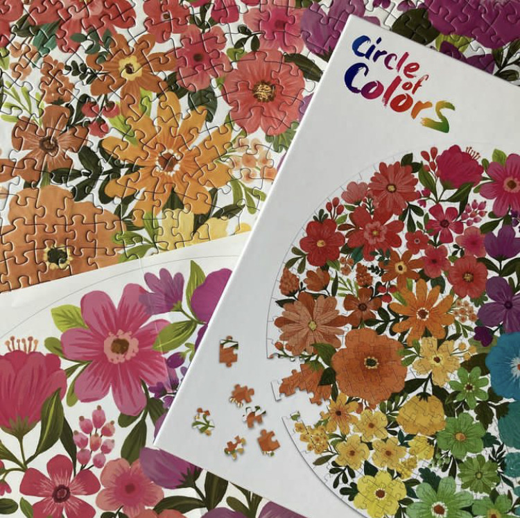 Colorful floral jigsaw puzzle with loose pieces beside the puzzle box
