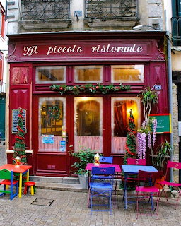 Red Italian restaurant facade with outdoor cafe seating and warm interior lighting