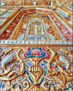 Ornate baroque ceiling with golden frames, painted frescoes, and decorative sculptural elements