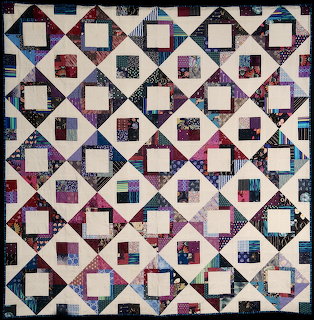 Patchwork quilt with geometric square pattern in burgundy, navy, pink and cream fabrics