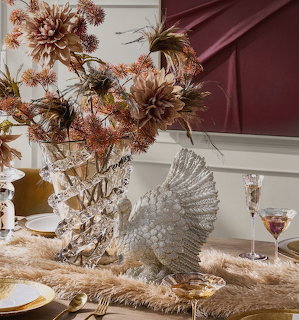 Elegant table display with crystal vase, dried autumn flowers, silver swan figurine, and champagne glasses