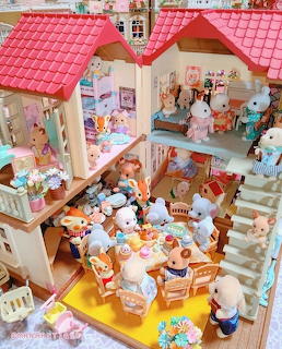 Multi-story Calico Critters dollhouse with animal figures, furniture, and red roof