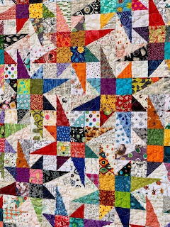 Colorful patchwork quilt with triangular blocks in various printed fabrics