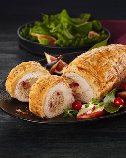 Sliced puff pastry tenderloin with cranberry filling on a dark plate with salad and figs