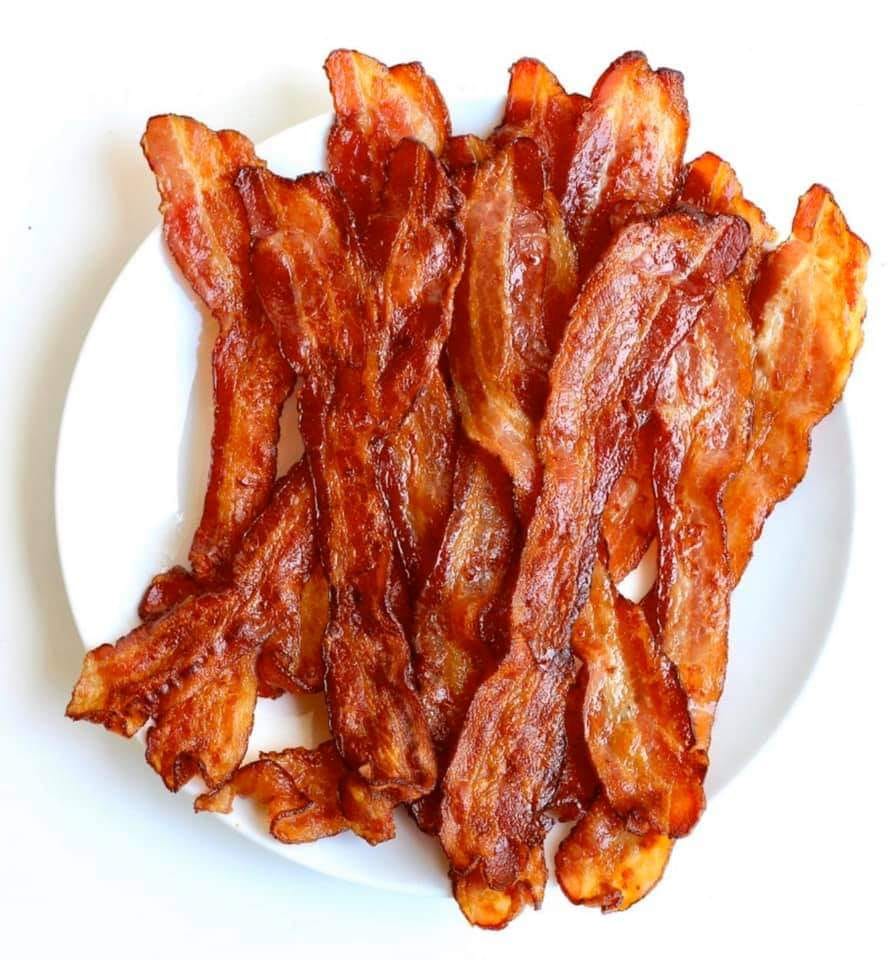 Several strips of crispy cooked bacon arranged on a white plate