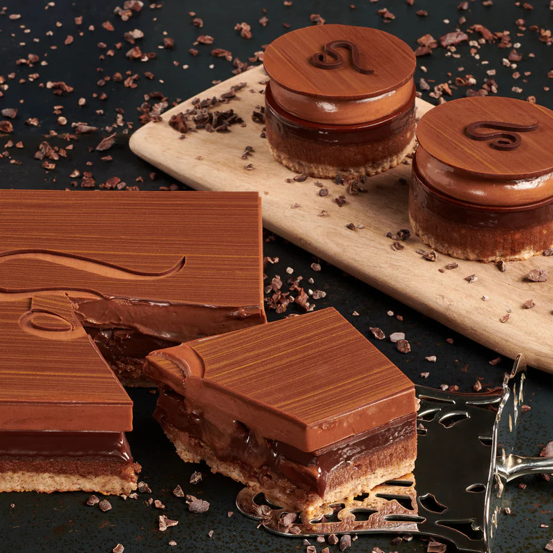 Chocolate layered desserts with hazelnuts on marble board with coffee beans