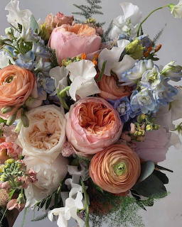 Close-up of a pastel floral bouquet with peach, pink, white, and blue flowers