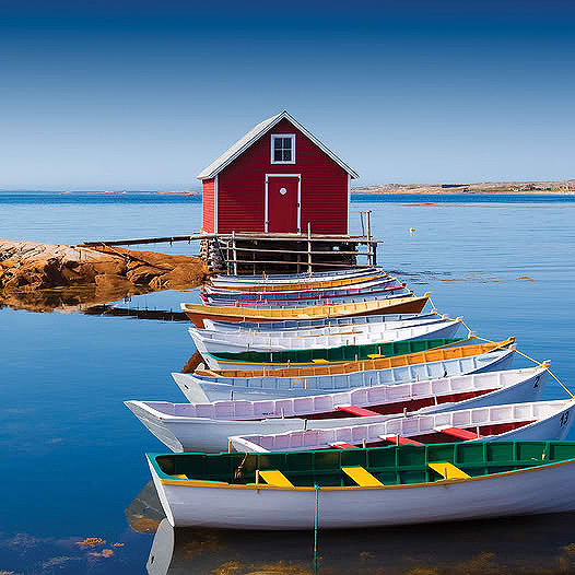 Colorful rowboats on calm water with a red boathouse in the background