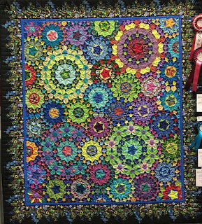 Colorful patchwork quilt with circular floral patterns on a dark background
