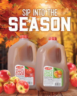 Two apple cider jugs surrounded by red apples and autumn leaves