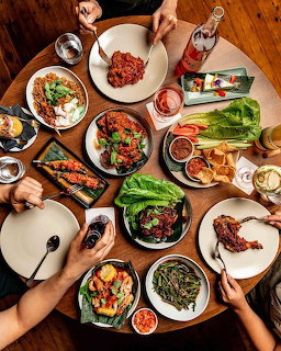 Overhead view of Asian dishes and hands sharing a meal on a wooden table