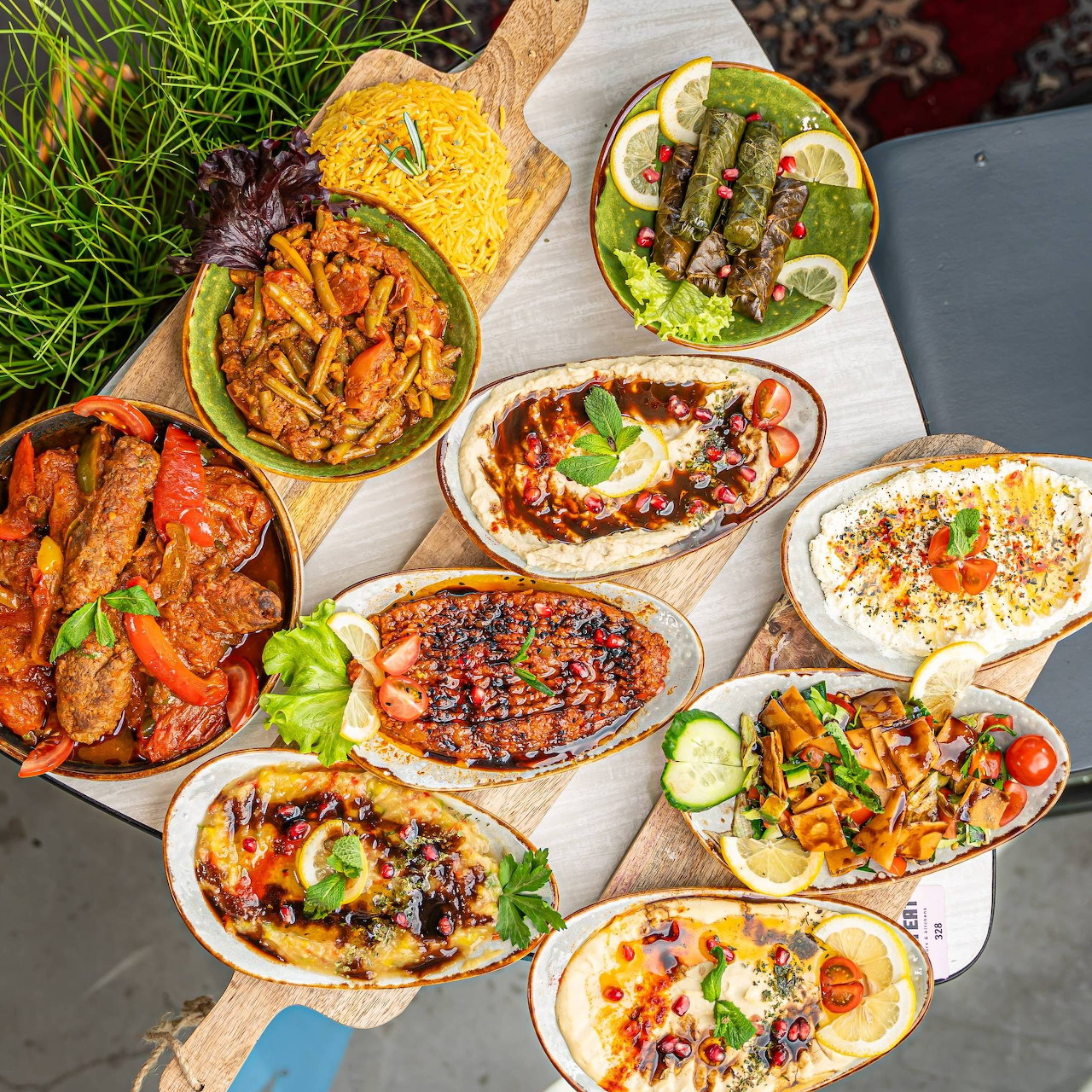 Colorful Middle Eastern food spread with hummus, falafel, grilled meats and fresh vegetables on oval plates