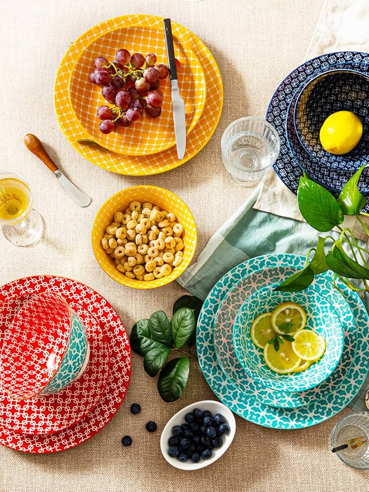 Colorful ceramic plates and bowls with food ingredients arranged overhead on white table