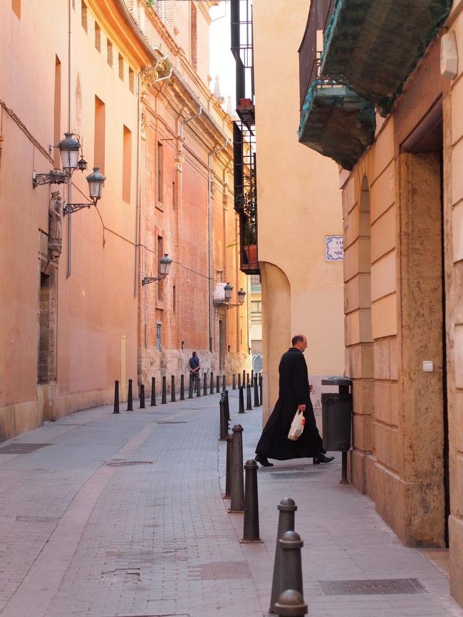 Narrow street in Valencia with yellow-orange buildings and a person walking