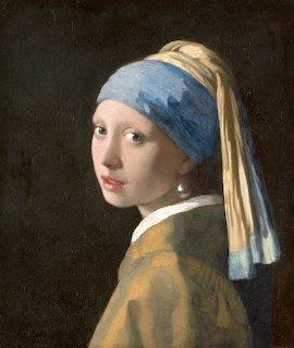 Portrait of young woman in blue turban and pearl earring looking over shoulder on dark background