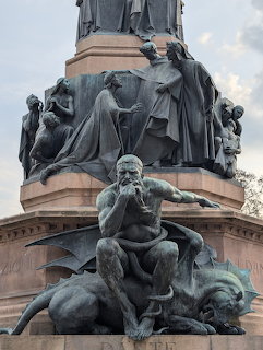 Bronze sculptures at the base of the Dante monument in Piazza Dante, Trento, Italy