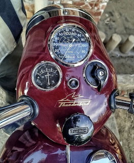 Burgundy Triumph Thunderbird motorcycle steering head with chrome gauges and instruments