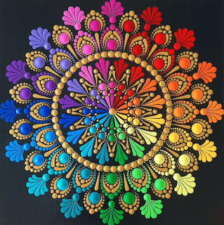 Colorful circular mandala with rainbow gradient radiating from center in ornate fractal pattern on black background