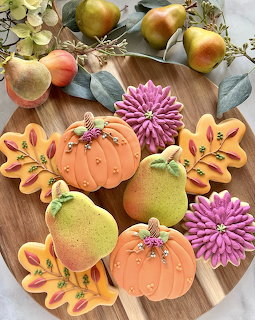 Colorful autumn-themed decorated cookies with pumpkins, pears, leaves and flowers on wood board