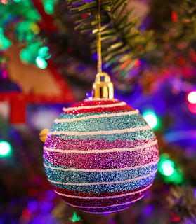 Striped glitter Christmas bauble hanging on a tree with colorful bokeh lights